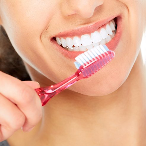 Woman with bright smile preparing to brush her teeth