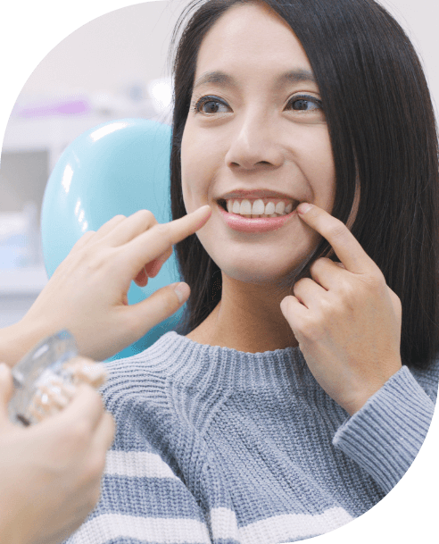 Woman pointing to smile after tooth replacement with dental implants