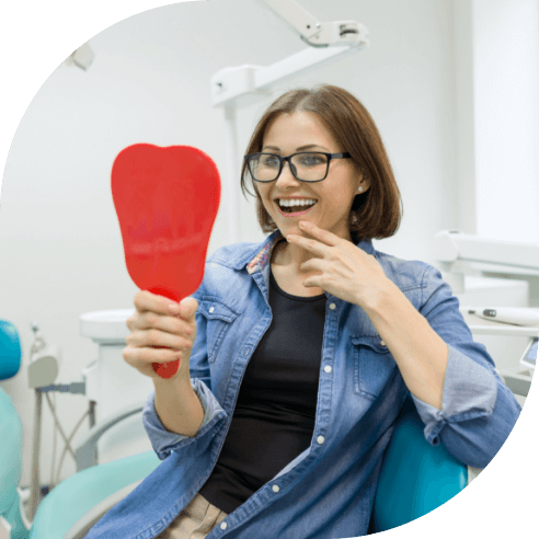 Woman looking at smile after tooth replacement with dental implants