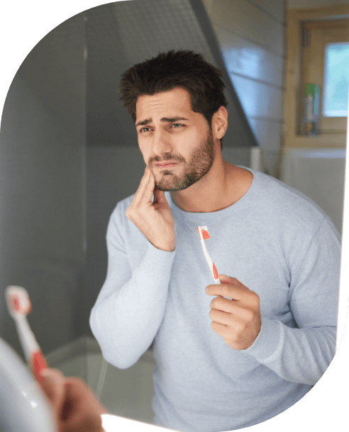 Man in need of emergency dentistry holding cheek in pain