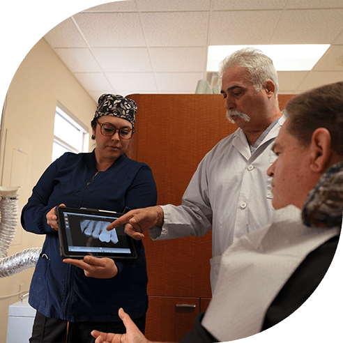 Dentist dental team member and patient looking at x-rays during dental checkup and teeth cleaning visit