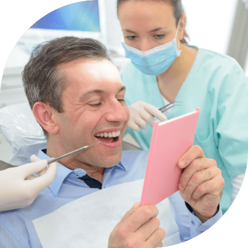 Man looking at smile after dental crown and bridge restoration