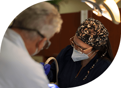 Dentist and dental team member removing amalgam filling