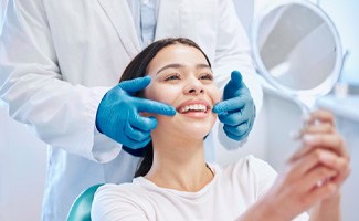 Happy dental patient using mirror to admire the results of her treatment