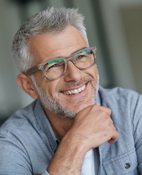 Man with glasses smiling after getting veneers in Albuquerque, NM