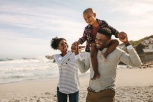 a family smiling on the beach after the parents got professional teeth whitening